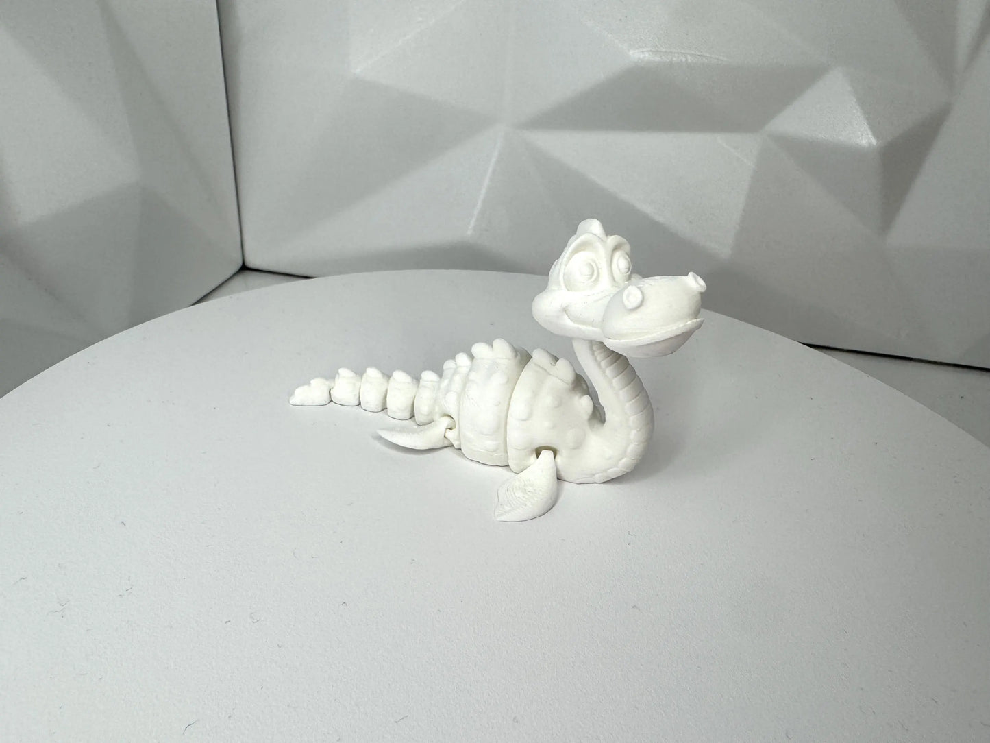 Weisse 3d-gedruckte Nessie-Figur in aufrechter Pose vorne, klein, Kopf beweglich, segmentierter Körper