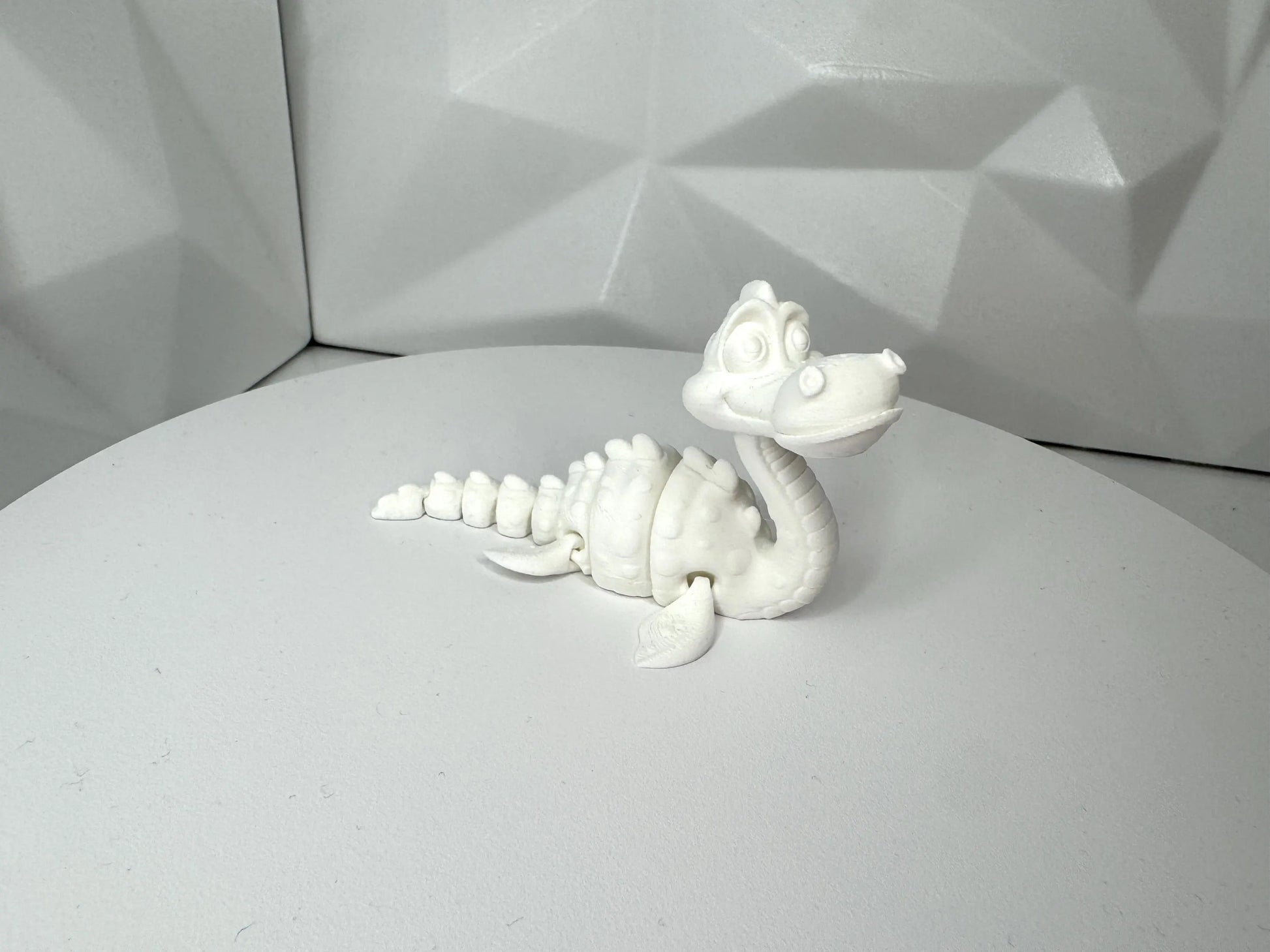 Weisse 3d-gedruckte Nessie-Figur in aufrechter Pose vorne, klein, Kopf beweglich, segmentierter Körper
