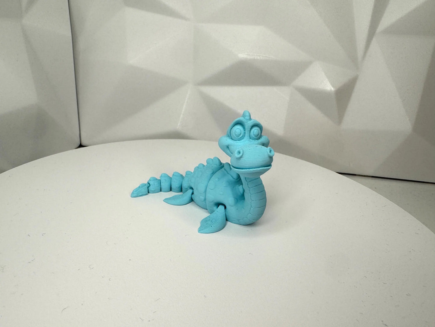 Hellblaue 3d-gedruckte Nessie-Figur in aufrechter Pose vorne, klein, Kopf beweglich, segmentierter Körper